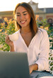 © Paulista - Attractive young freelance or student holding a cup of coffee, smiling and working on laptop.