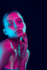 Young beautiful girl with well-kept skin and without makeup isolated over dark background in neon light. Concept of beauty, art, cosmetics and youth