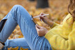 © primipil - Young woman model sitting with tablet pc and painting with pencil stylus in autumn park with yellow foliage maple leaves.