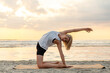 Leinwandbild Motiv fitness, sport, and healthy lifestyle concept - woman doing yoga camel pose on beach over sunset