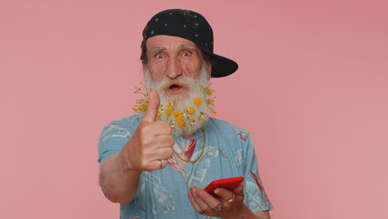 Mature man flowered beard using mobile phone typing new post on web sms message, browsing, searching addiction of social networks. Senior grandfather studio shot isolated alone on pink background