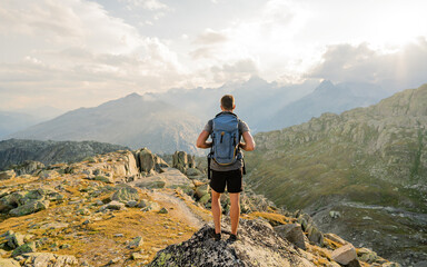 hiker at the top of the pass with a backpack to enjoy a sunny day in the alps. mountain lake nearly 