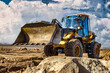 © Anoo - Powerful bulldozer or loader moves the earth at the construction site against the sky. An earthmoving machine is leveling the site. Construction heavy equipment for earthworks.
