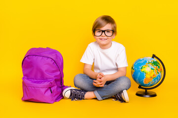 Sticker - Portrait of handsome cheerful curious pre-teen boy sitting visit classes isolated over bright yellow color background