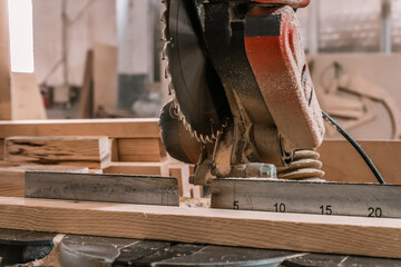 Sawing machine for wood in the workshop for the production of furniture. Woodworking circular saw and wooden bar for cutting.