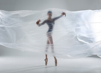 Wall Mural - Ballerina in dark ballet leotard dancing on ballet pointe shoes in white studio 