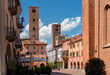 View of Duomo square with the town hall among old houses and medieval towers under beautiful sky in Alba, Langhe, Piedmont, Italy.