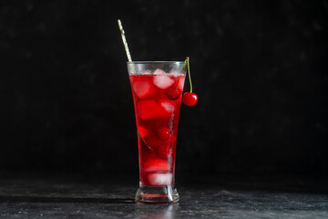 Wall Mural - Fresh red cherry cocktail with ice cubes in glass on black background. Summer iced refreshing drink