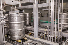 Brewery, Bottling Beer On Aluminum Kegs On Conveyor Lines. Industrial Work, Automated Modern Food And Beverage Production.