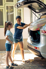 Wall Mural - Small family leaving on holiday road trip with inflatable and baggage in automobile trunk. Mother with young kid going on summer vacation at seaside. Going on journey adventure with vehicle.