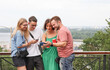 © serhii - a company of friends uses a smartphone takes a selfie on the background of the city panorama.