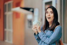 Cheerful Woman Holding Cash Money In Front Of An ATM Machine. Happy Person Winning Extra Dollars With Passive Income Ideas
