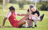 Fototapeta  - Soccer, sports and injury of a female player suffering with sore leg, foot or ankle on the field. Painful, hurt and discomfort woman getting her pain checked out by athletic trainer on the pitch.