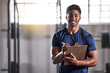 © Alexis Scholtz/peopleimages.com - Gym, workout and personal trainer with clipboard consulting at a training sports in gym. Portrait of muscular, active and smiling fitness coach writing on health, wellness and exercise with flare