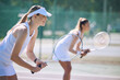 © Michael Cunningham/peopleimages.com - Fun women playing tennis match, practicing for competition and getting ready for sporty fitness game on a court outside, Female friends and teammates doing cardio training and sports workout together