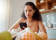 © K Abrahams/peopleimages.com - Healthy, wellness lifestyle woman sitting at home kitchen table scrolling on social media on her phone during breakfast. Young female enjoying her cup of coffee while texting in the morning