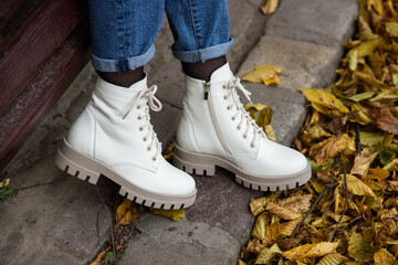 Wall Mural - Female legs in a jeans and white fashion boots with laces.