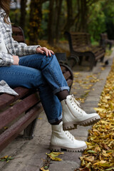 Wall Mural - Female legs in a jeans and white fashion boots with laces.