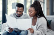 © Nicholas Felix/peopleimages.com - Married couple planning their finance and budget bills or papers together at home. Serious husband and young wife looking at household financial report information and insurance money plan