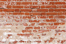 An Old Red Brick Wall With Remnants Of Plaster.