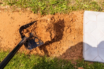 the construction shovel is filled with sand when laying the garden path with tiles in a country house. construction work.