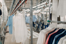 Dry Cleaning Clothes. Clean Cloth Chemical Process. Laundry Industrial Dry-cleaning Hanging Clothes On Rack
