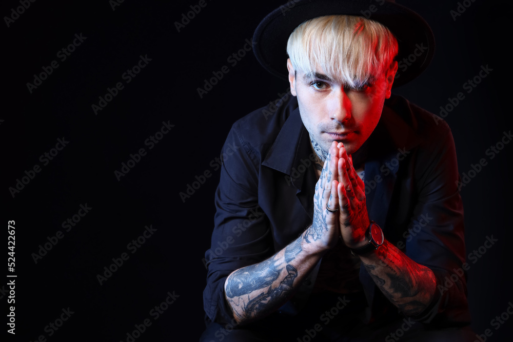 Young tattooed man on black background