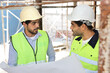 © feeling lucky - Two technician civil engineer or specialist inspector discussing, brainstorm and planing work with laptop, blueprint and walkie talkie radio together at Industrial building site. Construction concept