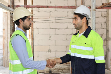 Two technician civil engineer or specialist inspector shaking hands celebrate successful together completed deal commitment at Industrial building site. Construction concept