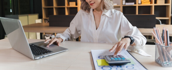 Wall Mural - businesswoman sitting working on laptop and use calculating machine analysis document income work invoice bill bank
