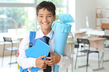 Wall Mural - Little boy with blue school cone and books in classroom