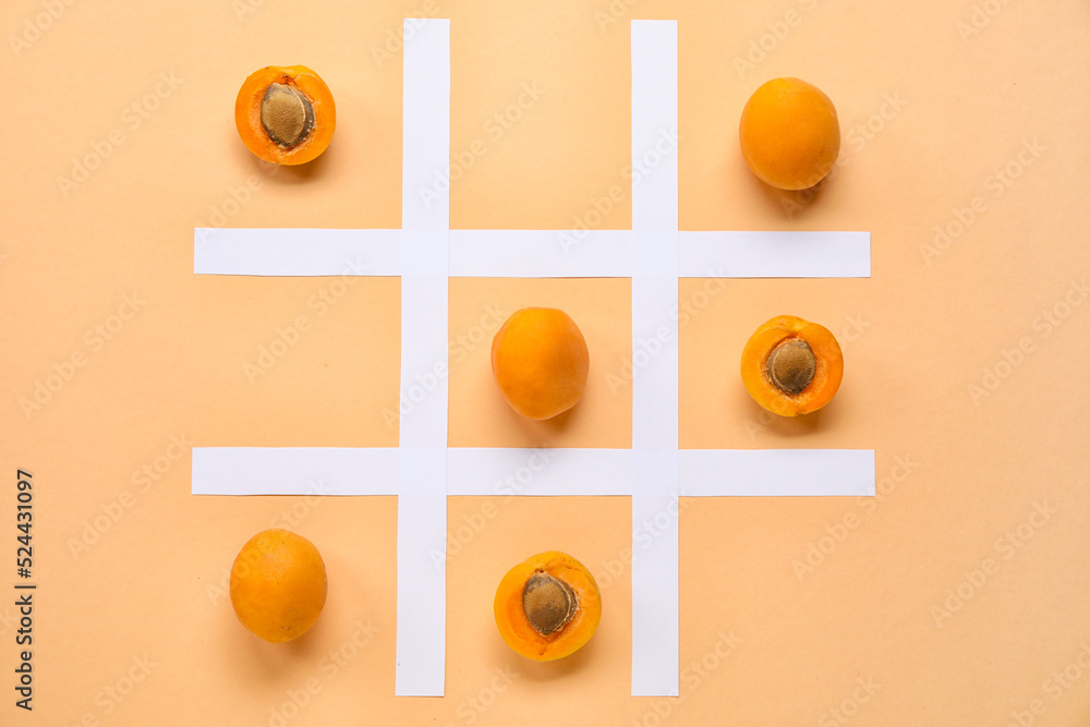 Tic tac toe game with ripe apricots and paper grid on color background