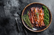 Hot Fried crunchy Bacon sizzling slices in plate with herbs. Black background. Top view. Copy space