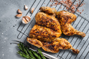 Canvas Print - Traditional spatchcocked barbecue chicken on grill. Gray background. Top view