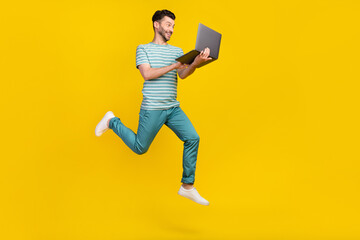 Poster - Profile full length photo of impressed guy run with laptop wear t-shirt jeans sneakers isolated on yellow color background