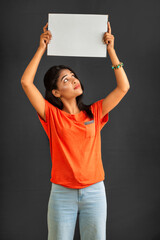 Poster - A young girl or businesswoman holding a signboard in her hands on a gray background.