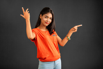 Sticker - Portrait of a successful cheerful young girl pointing and presenting something with hand or finger with a happy smiling face.