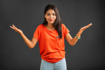 Wall Mural - Portrait of a successful cheerful young girl holding and presenting something on hand with a happy smiling face.