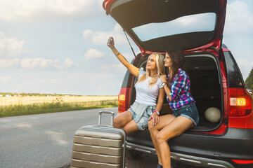 Wall Mural - Young pretty women friends travel by car. Summer holidays and active recreation. Positive emotions from the adventure, Girls take a selfie