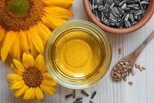 Sunflower Oil In Glass Bowl And Seeds On Wooden Table, Flat Lay