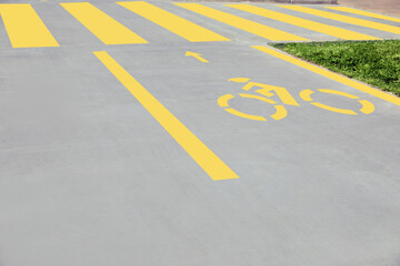 Wall Mural - Bike lane with painted yellow bicycle sign and arrow near pedestrian crossing