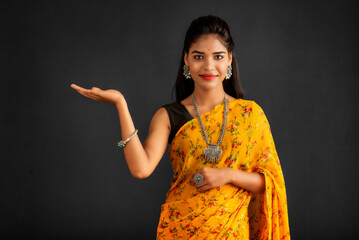 Sticker - Portrait of a successful cheerful young girl holding and presenting something on hand with a happy smiling face.