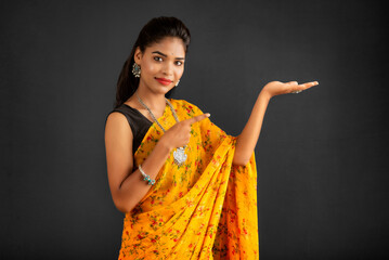 Poster - Portrait of a successful cheerful young girl holding and presenting something on hand with a happy smiling face.