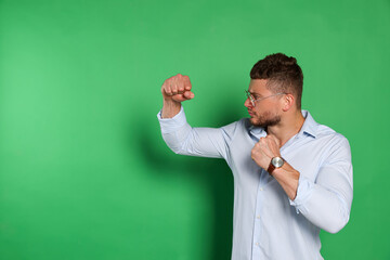 Young man ready to fight on green background, space for text