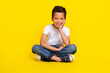 © deagreez - Full length photo of little boy sit wear t-shirt jeans sneakers isolated on yellow color background