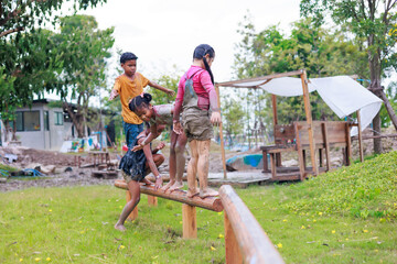 Wall Mural - Kids climb on wooden railling. Diverse happiness kid group playing in playground at summer camp learning