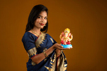 Happy young Indian woman posing with Ganesha statue on the occasion of Ganesh Festival