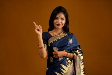 Poster - Portrait of a cheerful young girl or woman pointing something with a happy smiling face.