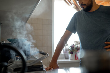 a man at home in the kitchen cooks cutlets on the grill