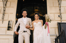 Stylish Stunning Couple Together On Their Wedding Day Against The Backdrop Of A City Hotel. Luxury Wedding Of A Beautiful Couple